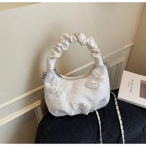 Detail of white lace handbag featuring textured pleat handles and 3D butterfly appliqués