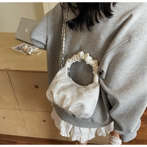 Detailed embroidery of white floral and butterfly patterns on a lace hobo handbag