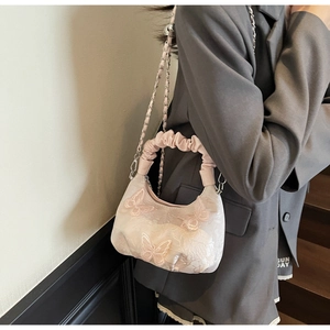 Detail of light pink butterfly embroidered bag with satin handle and silver chain strap