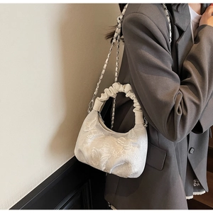 Detail of white butterfly embroidery and ruffled handle on an elegant evening handbag