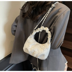 Detail of white butterfly embroidery and ruffled handle on small crossbody bag