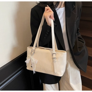 Detail der cremefarbenen Lacktasche mit Spitzenschleife und verstellbarem Gurtband
