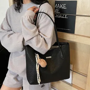 Minimalist black woven texture tote bag with plush bear charm shown in a lifestyle setting