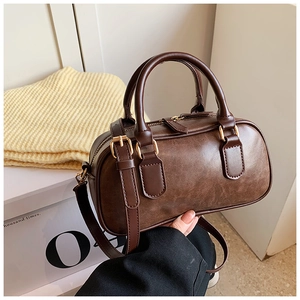 Close-up of retro brown boston bag with matte finish and gold hardware accents