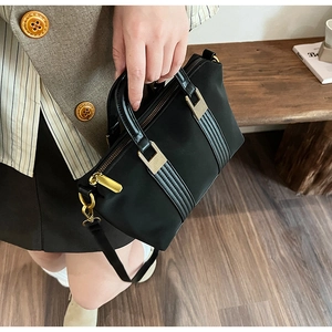 Detail of black nylon tote bag with vertical stripes and matte gold hardware accessories