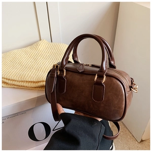 Detailed close-up of dark brown vintage Boston bag with gold-tone hardware and leather texture