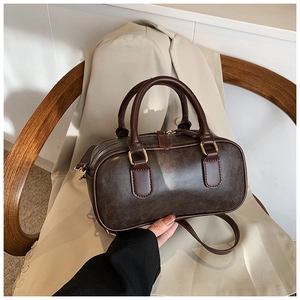 Detail of vintage brown leather Boston bag with gold hardware and textured finish