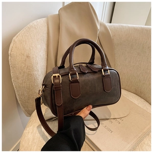 Detail of retro dark brown cylinder handbag with gold hardware and grain texture