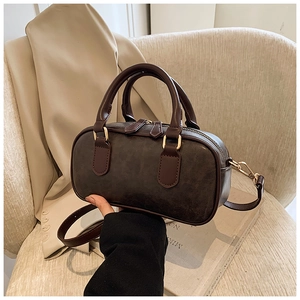 Detail of retro textured dark brown handbag with dual handles and gold metal hardware