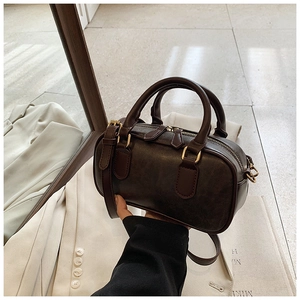 Detailed macro view of dark brown Boston bag with golden zippers and leather texture