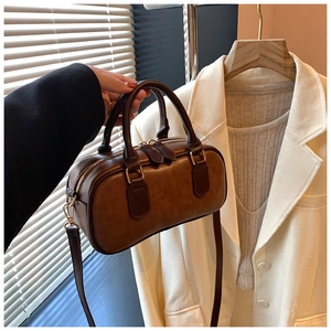 Detail of a brown Boston style handbag with vintage leather texture and gold hardware