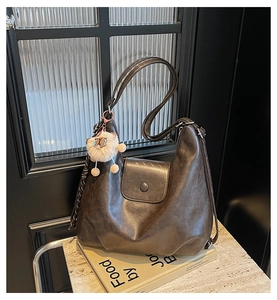 Close-up of vintage coffee brown tote bag featuring a round buckle and plush toy charm