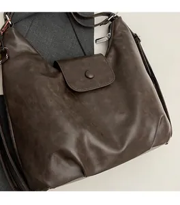 Detail of dark brown vintage tote bag showing retro leather texture and flap closure