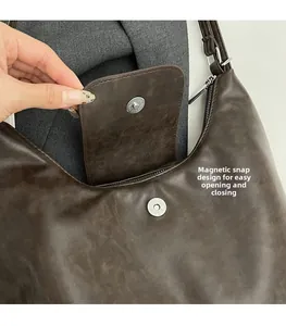 Close-up of brown tote bag featuring magnetic buckle and secure zipper closure