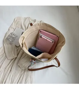 Spacious interior of woven straw tote bag with brown leather handles and zipper