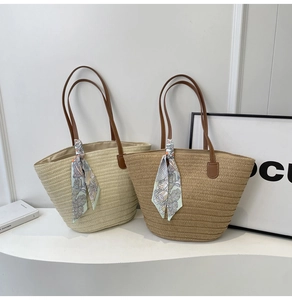 Detail of hand-woven straw tote with leather straps and floral silk scarf accessory