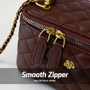 Detail of smooth gold zipper and quilted burgundy leather on chain shoulder bag