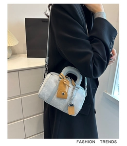 Detail of light blue denim Boston bag with caramel leather trim and silver metal zipper