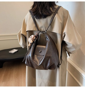 Detail of vintage dark brown tote bag showing smooth leather texture and plush doll charm