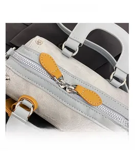 Detail of light blue woven Boston bag showing smooth silver double zipper and yellow leather trim