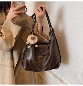Detail view of deep brown soft leather shoulder bag with plush charm and magnetic flap