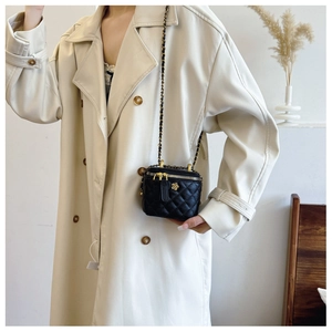 Detail of black quilted leather mini bag with gold floral clasp and chain strap
