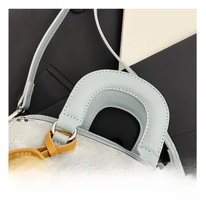 Detailed close-up of textured blue fabric, leather handle, and yellow pendant on the handbag