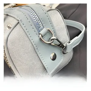Detailed macro of silver-tone zipper hardware and light blue textured fabric on handbag