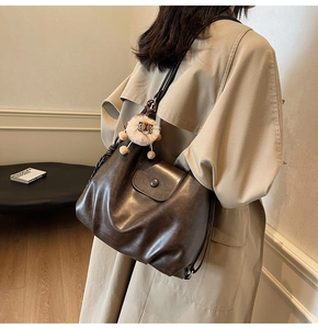 Detail of dark brown leather tote bag with soft texture and lion head pendant