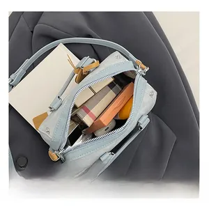 Internal capacity of light blue Boston bag showing cosmetics, lipstick, and earphones