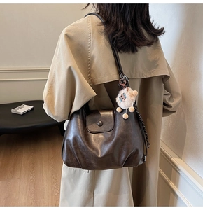 Deep brown leather tote bag with plush charm and polka dot scarf detail on model