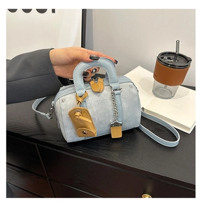 Detail of mini Boston bag in blue denim with brown leather handles and brand logo