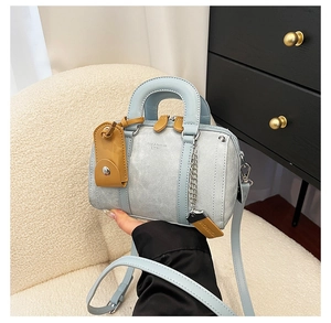 Detail of light blue Boston bag showing leather texture and debossed fashion branding