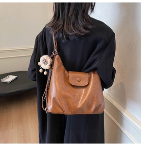 Brown faux leather hobo shoulder bag with a cute lion plush charm on a female model