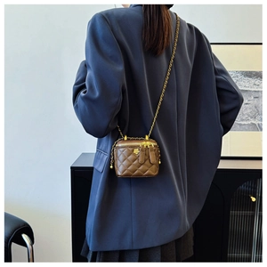 Close-up of brown quilted vanity case bag with gold camellia hardware and chain strap