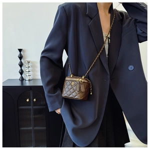 Detail of brown quilted mini bucket bag with gold flower charm and chain strap
