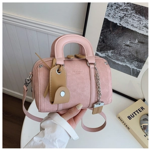 Detail of pink canvas Boston bag showing textured fabric, leather handle, and metal chain