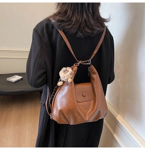 Brown retro leather tote bag with a cute plush lion pendant used as a stylish backpack