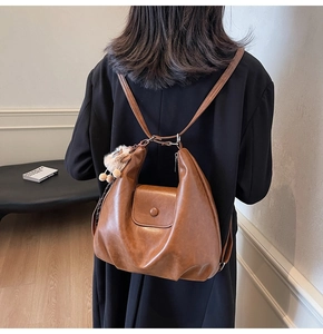 Detail of vintage brown PU leather backpack with decorative plush ball and textured flap