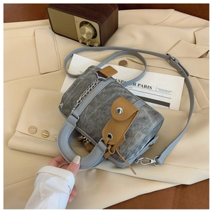 Close-up of grey washed denim Boston bag with leather trim and silver chain detail