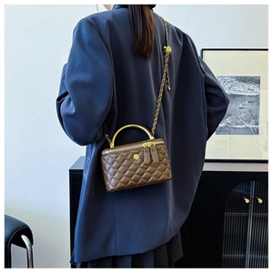 Brown quilted mini bucket bag with gold chain strap shown on person in a modern interior