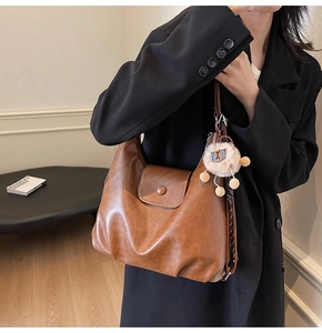 Close-up of brown PU leather tote bag with flap magnetic closure and plush charm