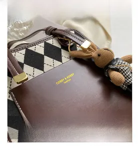 Detail view of monochrome quilted tote with leather patch and brown knit bunny charm