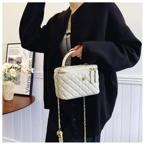 Detail of white quilted bucket bag with golden camellia clasp and chain strap