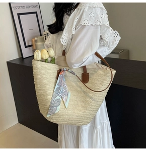 Straw tote bag detail with brown leather straps and colorful decorative floral silk scarf
