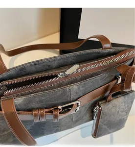 Detail van de gladde zilveren ritssluiting en leerstiksel op de grijze denim tas
