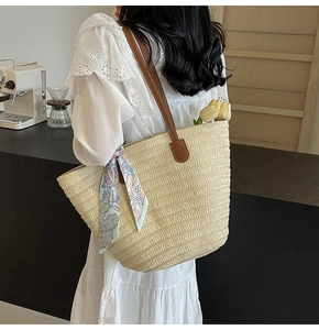 Straw tote bag with brown leather handles and printed silk scarf on a female model