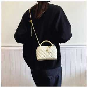White quilted bucket bag with chain strap shown on model for size perspective
