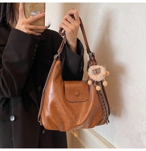 Side view of large brown soft leather tote bag with cute plush pendant and magnetic flap