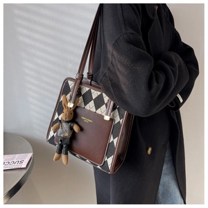 Close-up of quilted tote bag with brown leather pocket and cute rabbit charm detail